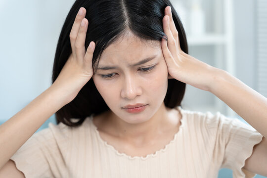 Headache, female having migraine pain, bad health, Asian woman feeling stress and headache, Office syndrome, sad tired touching forehead having migraine or depression, irritated girl, sadness grief