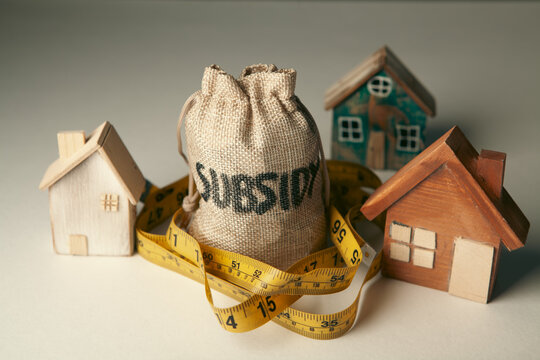 Money bag with house model on dark background. Real estate concept.