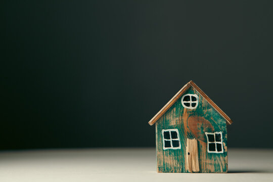 Miniature wooden house on a black background with copy space for text