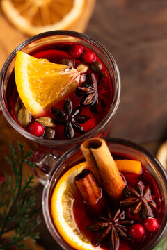 Warm mulled wine drink with orange slices and spices in glass mugs on wooden table
