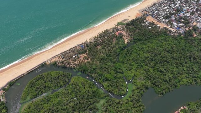 Aerial drone view of tropical beach with turquoise ocean waves, coconut palm trees, and backwater river estuary
