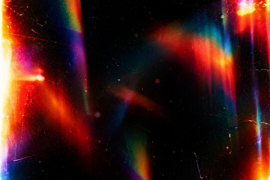 Abstract colorful light leak overlay on a deep black background, irregular soft-focus rainbow light leaks and glowing color blooms, vibrant red, orange, yellow, cyan, blue, magenta and subtle green to
