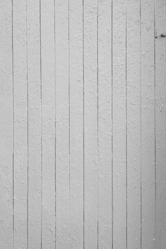 A white wooden wall made of vertical boards with peeling paint.