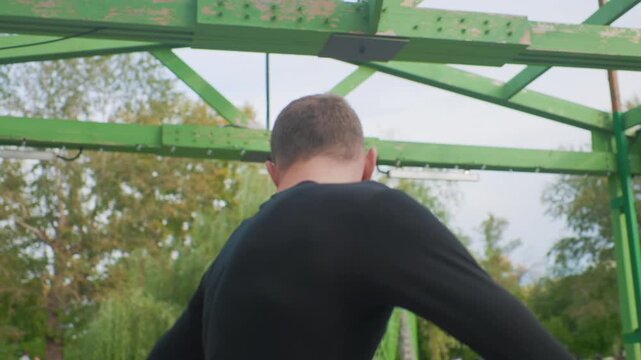 Individual rests peacefully beside water after training, Person takes moment to unwind near pond after exercise, Someone pauses for calming moment beside water following vigorous training session