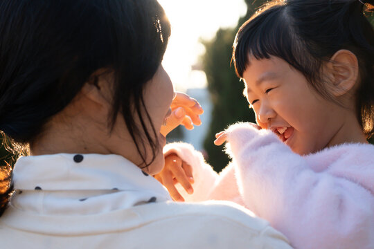 Happy Mother hugging and carry daughter playing together outdoors Family Childhood development and growth with love for her Mom's concern Happy baby's dream