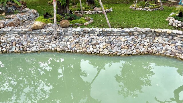 A small pond with rocks wall around in the middle of mini garden.