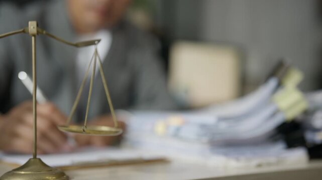 Lawyer Reviewing Legal Paperwork Beside Scales of Justice in Office