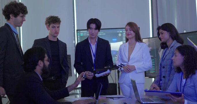 Business team in suits inspecting robotic hand prototype at conference table in meeting room