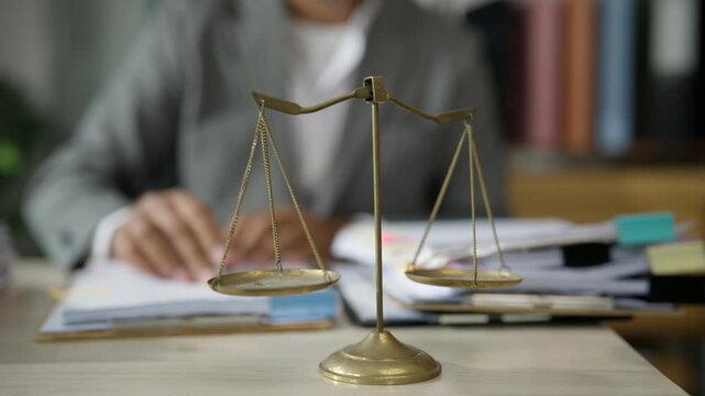 Legal Professional Signing Documents with Scales of Justice on Desk