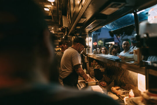 View from inside a food truck kitchen through the service window at waiting customers