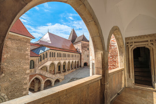 Corvin Castle in Hunedoara: imposing Gothic-Renaissance fortress with stone steps, arches and layered courtyards under a vivid blue sky, showcasing medieval Romanian heritage of Transylvania
