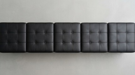 Naklejka premium Top View of Five Black Tufted Synthetic Leather Ottoman Stools Arranged in a Line on a Gray Floor for Modern Interior Design