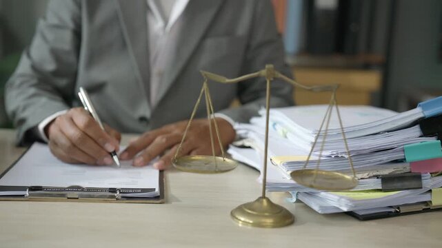 Legal Professional Reviewing Documents with Scales of Justice at Office Desk