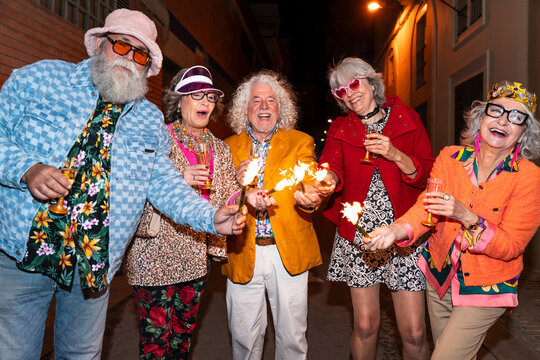Group of happy senior friends with fancy clothing having party in the night