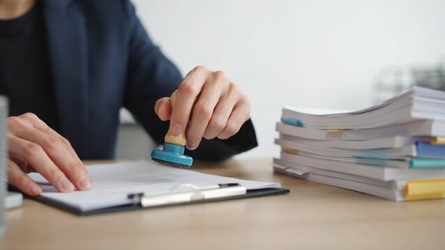 Corporate attorney stamping official document on clipboard next to thick stack of files.