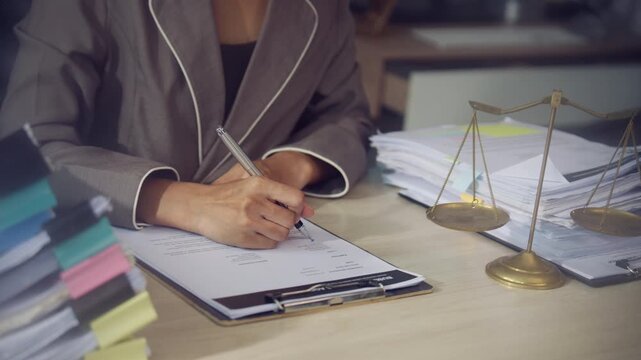 Legal Professional Signing Documents with Scales of Justice on Office Desk