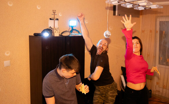Excited family having fun together with dancing and music at home party