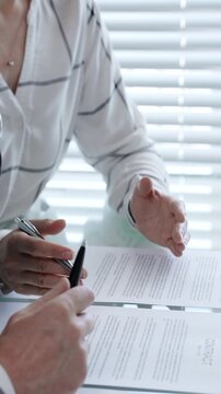 Business woman explaining contract details to a client, pointing to important clauses with a pen during a professional meeting or negotiation, finalizing agreement