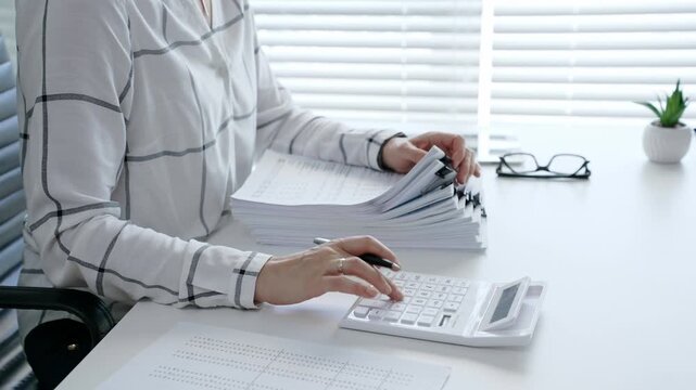 Financial professional carefully reviewing business documents with a magnifying glass while calculating numerical data, demonstrating diligent tax preparation and detailed audit analysis