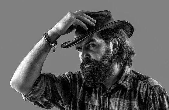 Cowboy style in a plaid shirt. Man adjusting his cowboy hat. Man unshaven cowboys. American cowboy. Black and white