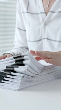 Accountant or financial professional reviewing business documents and calculating expenses on a white desk, managing taxes, financial records, and official paperwork for audit or reporting