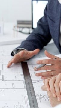 Architects discussing building blueprints and architectural plans for a new construction project, collaborating on design ideas and engineering solutions in a modern office