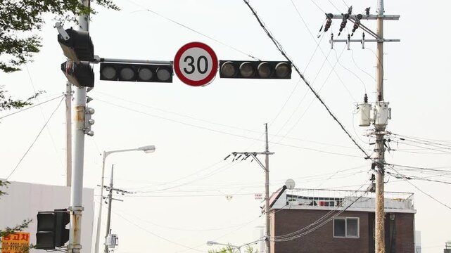 신호등과 30 제한 속도 표지판, 전봇대, 주변 건물이 있는 도로 풍경을 담은 뷰
