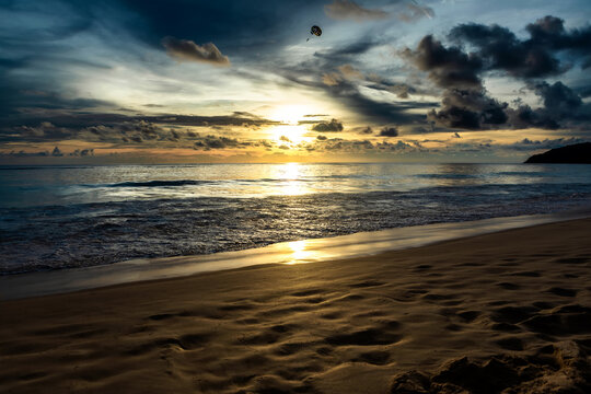 Golden sunset over the sea with sun breaking through clouds and glittering reflection on ocean water
