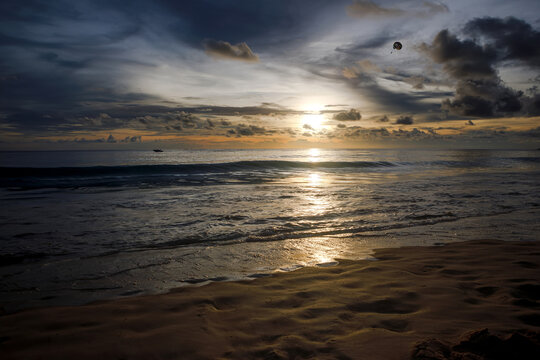 Golden sunset over the sea with sun breaking through clouds and glittering reflection on ocean water
