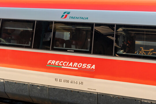 Barletta, Italy - Aug 1, 2026: Frecciarossa lettering and Trenitalia logo on the side of a red and silver high speed train carriage with passenger windows and vehicle number