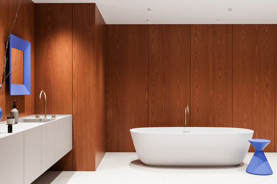 Contemporary walnut bathroom interior with freestanding white bathtub, sculptural blue stool, minimalist vanity, and warm modern cabinetry design. 3D Rendering