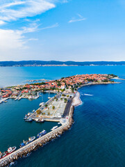 Fototapeta premium Coastal view of a harbor with boats and a distant town under a blue sky