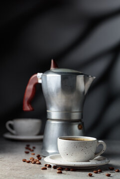 Cup of espresso and classic Italian aluminium moka pot on a gray stone table.