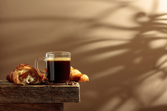 Black coffee with croissants on an old wooden table.