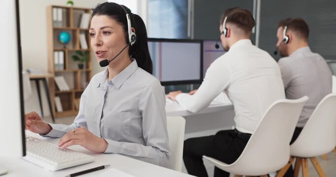 Call center woman operator with headset support. Smiling agent at computer in an office handles customer service calls and chats with communication. Concept of friendly professional assistance.