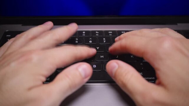 A man is typing on his laptop in slow motion, top down POV view