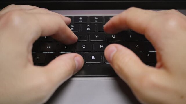 A man is typing on his laptop in slow motion, top down POV view
