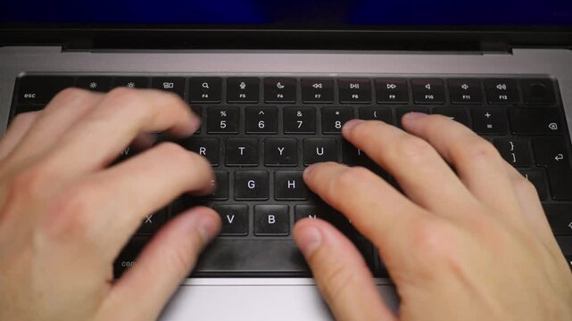 A man is typing on his laptop in slow motion, top down POV view
