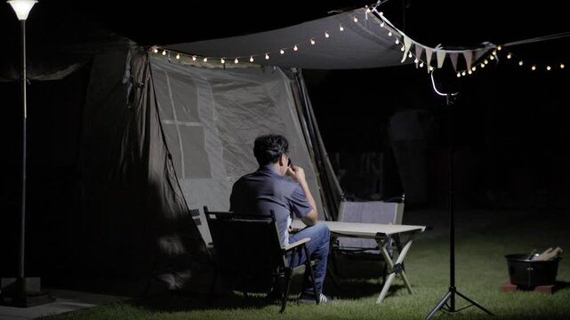 Drinking a Beverage at a Backyard Campsite at Night
