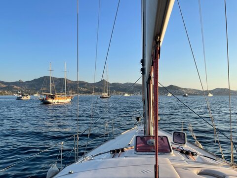 Sailing yacht deck view with white sails and blue sea on a sunny day.