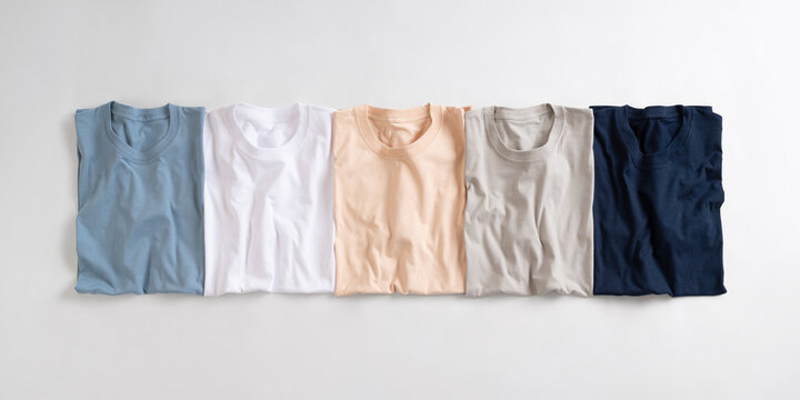 Flat lay of five folded blank t shirts in assorted pastel and neutral colors on a white background
