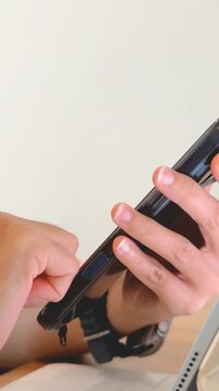 Close-up of hands holding a smartphone, interacting with its side buttons and features.