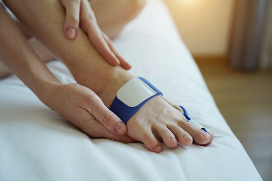 Woman applying a blue hallux valgus splint as part of a self-care recovery routine at home