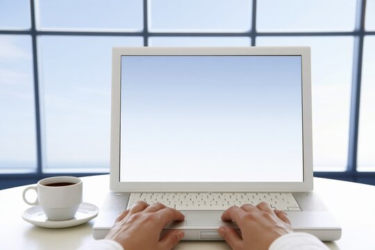 Hands typing on laptop with coffee cup and window background