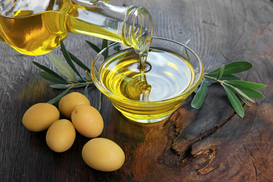 Organic olive oil pouring from a glass carafe into a glass bowl