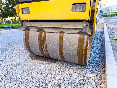 Construction equipment compacts gravel on road site in city during daytime