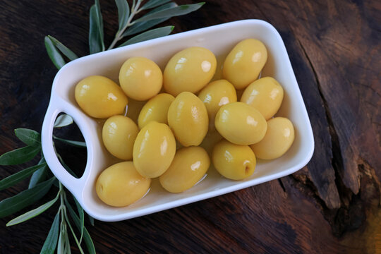 green olives in a bowl on wooden table