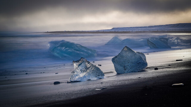 Small blue icebergs on the famous Diamond Beach, dark sky, Jokulsarlon, Iceland