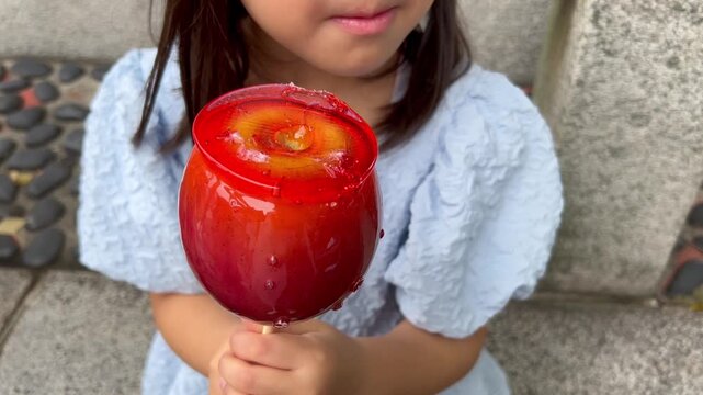 りんご飴を食べる幼児