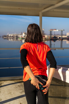 Woman in sportswear stretching her leg by a river, preparing for an active outdoor workout